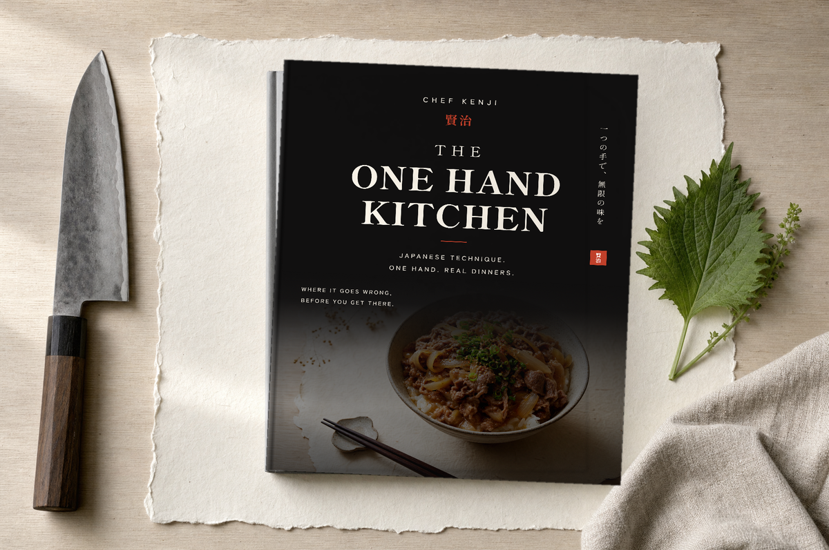 The book beside a Japanese chef knife and a sprig of shiso
